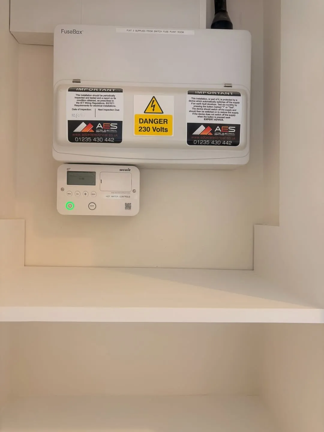 Consumer unit with Adtec contact labels above a hot water controller